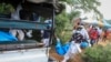 Police and local residents load the exhumed bodies of victims of a religious cult into the back of a truck in the village of Shakahola, near the coastal city of Malindi, in southeastern Kenya, April 23, 2023.