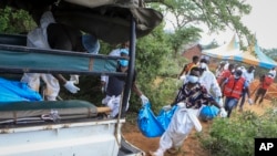 Police and local residents load the exhumed bodies of victims of a religious cult into the back of a truck in the village of Shakahola, near the coastal city of Malindi, in southeastern Kenya, April 23, 2023.