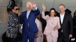 Prezidan Joe Biden kanpe sou sen nan ak chante Charlie Wilson (a goch) pandan Vis Prezidan Kamala Harris ak mari li, Doug Emhoff salye foul la pandan konse Juneteenth Lamezonblanch la 10 Jyen 2024. 