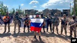 Photo by Prigozhin Press Service, May 20, 2023. Wagner chief Yevgeny Prigozhin holds a Russian national flag in front of his soldiers in Bakhmut, Ukraine. 