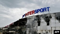 An employee looks through the debris of a destroyed French sporting goods retailer, Intersport, at a shopping mall in Bucha, Kyiv region, Aug. 16, 2022, 