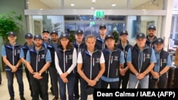 This picture released Aug. 29, 2022 on the official Twitter account of the International Atomic Energy Agency shows IAEA chief Rafael Grossi (C) posing with a team of 13 people wearing caps and sleeveless jackets bearing the nuclear watchdog's logo. (AFP 