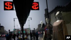 People walk past a currency exchange office screen displaying the exchange rates of U.S. Dollar and Euro to Russian Rubles in Moscow's downtown, Russia, March 29, 2022.