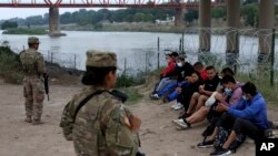 Migran ki te travese rivye Rio Grande a pou antre Ozetazini anba detansyon Gad Nasyonal la ann atandan y ap tann arive ajan Gad Frontye Etazini nan Eagle Pass, Texas, Vandredi 20 Me, 2022. 