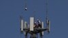 Workers install 5G telecommunications equipment on a T-Mobile tower in Seabrook, Texas, May 6, 2020.