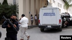 Un policía custodia frente a un vehículo de la oficina forense a la entrada de un hotel de Cancún, México, después de un tiroteo en que murieron dos personas el 4 de noviembre de 2021.