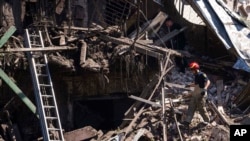 Rescue worker and police officer inspect a site of destroyed house after a Russian attack in a residential neighborhood in downtown Kharkiv, Ukraine, July 9, 2022.