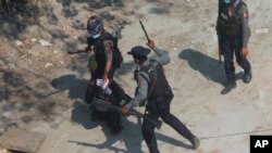  In this March 6, 2021, file photo, riot police officers hold down a protester as they disperse protesters in Tharkata Township on the outskirts of Yangon, Myanmar. 