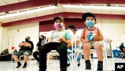 FILE - Oliver Estrada, 5, front left, waits with his brother Adriel, 2, after Estrada received the first dose of the Pfizer COVID-19 vaccine at an Adelante Healthcare community vaccine clinic at Joseph Zito Elementary School, in Phoenix, Nov. 6, 2021. 