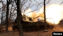 Ukrainian service members fire an artillery piece in the Donetsk region