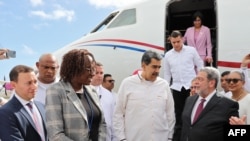 (FILES) This handout picture released by the Venezuelan Presidency shows Venezuela's President Nicolas Maduro (C) talking with Prime Minister of Saint Vincent and the Grenadines Ralph Everard Gonsalves (R) upon landing at Argyle International Airport in A