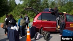 Imigran ayisyen ki sou fowntyè Etazini pataje ak Kanada nan zòn Champlain, New York, Etazini 3 out 2017. REUTERS/Christinne Muschi. 