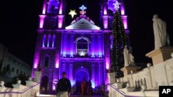 Moun pase bo kote Katedral Sen Joseph la ki limen pou fet Nwel la nan Hyderabad, peyi End, Vandredi 24 Dec. 2021.