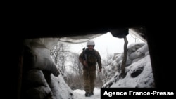 A Ukrainian Military Forces serviceman walks along a snow covered trench on the front line with the Russia-backed separatists near Zolote village, in the eastern Lugansk region, on Jan. 21, 2022.