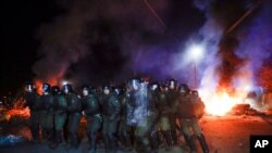 Ukrainian riot police prepare to push back demonstrators, who planned to stop buses carrying passengers evacuated from the Chinese city of Wuhan, outside Novi Sarzhany, to protest against their arrival.