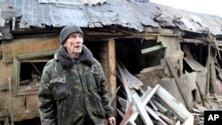 An elderly local citizen stands between debris of his house in the aftermath consequences of Ukrainian shelling, in the territory controlled by pro-Russian militants, eastern Ukraine, Feb. 24, 2022.