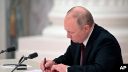 Russian President Vladimir Putin signs a document recognizing the independence of separatist regions in eastern Ukraine in the Kremlin in Moscow, Feb. 21, 2022. 