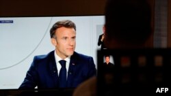 A man watches France's President Emmanuel Macron on a television screen in Paris during a live interview broadcasted on the French TV channel TF1's evening news and French public television news channel France 2 on September 24, 2023. (Photo by Geoffroy V