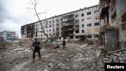 British volunteers Chris and Dave search for local residents to evacuate in a yard of a damaged apartment building in Bakhmut